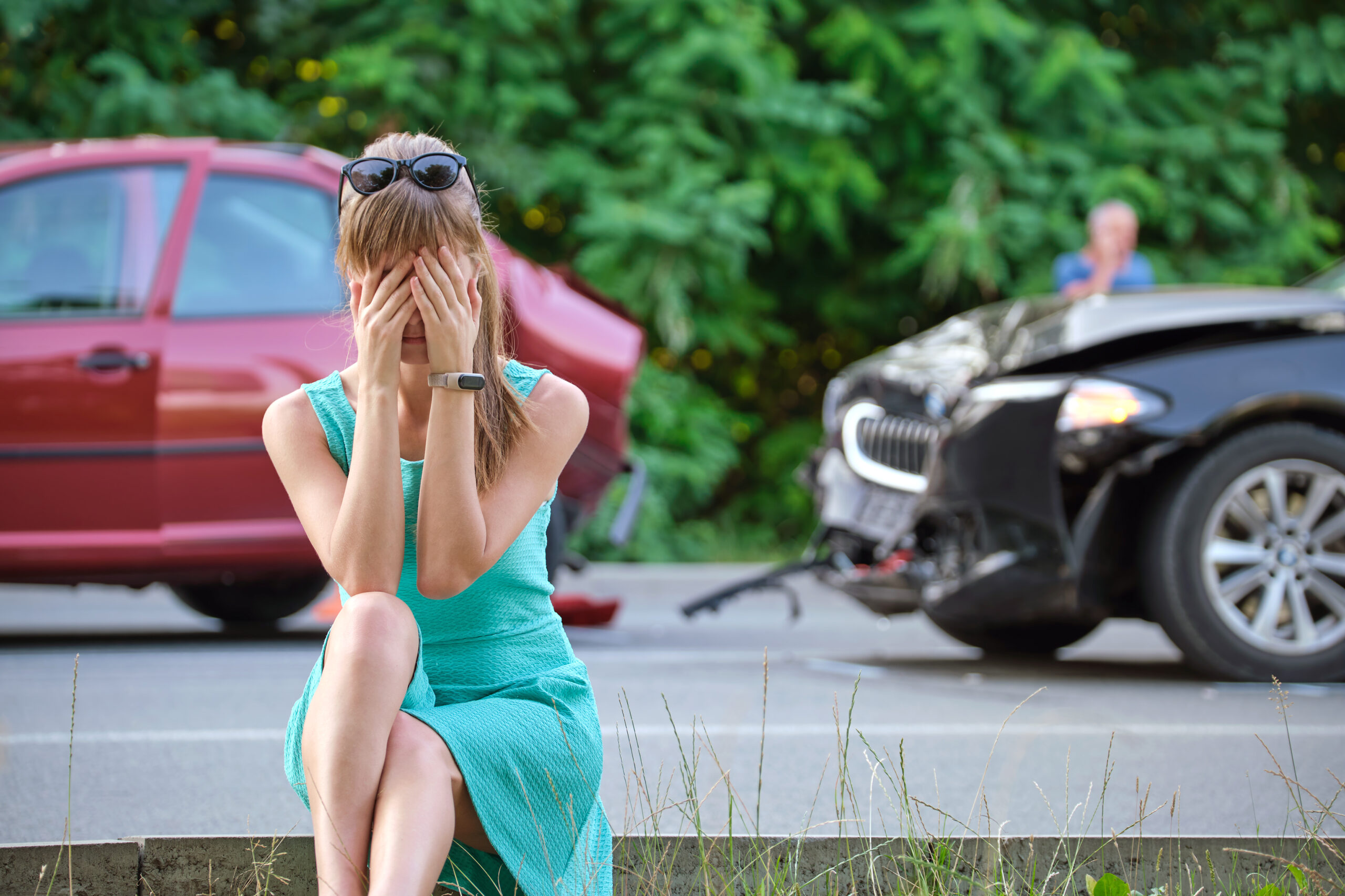 Stressed woman driver sitting on street side shocked after car accident.